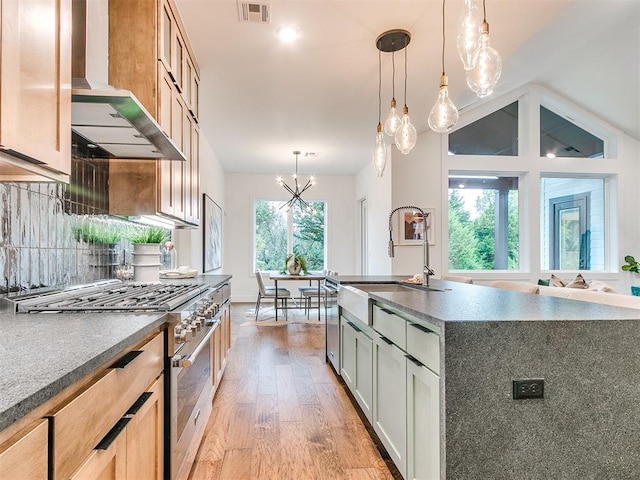 kitchen featuring visible vents, light wood-style floors, appliances with stainless steel finishes, wall chimney range hood, and backsplash