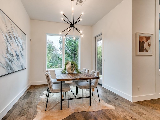 dining space with baseboards, wood finished floors, visible vents, and a notable chandelier