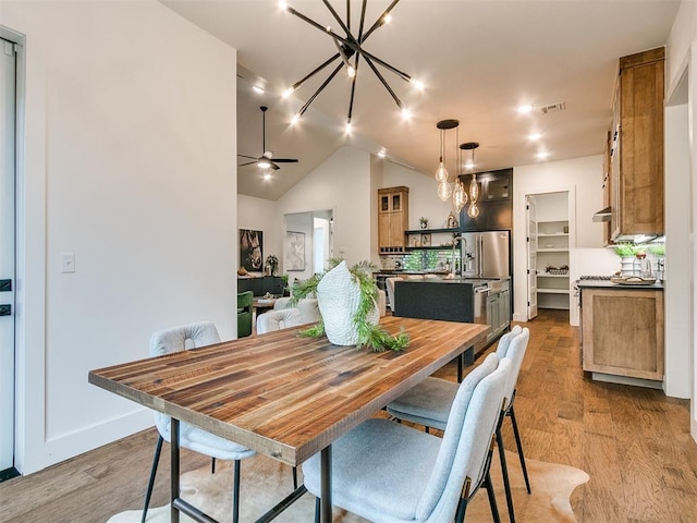 dining area featuring vaulted ceiling, wood finished floors, visible vents, and a ceiling fan