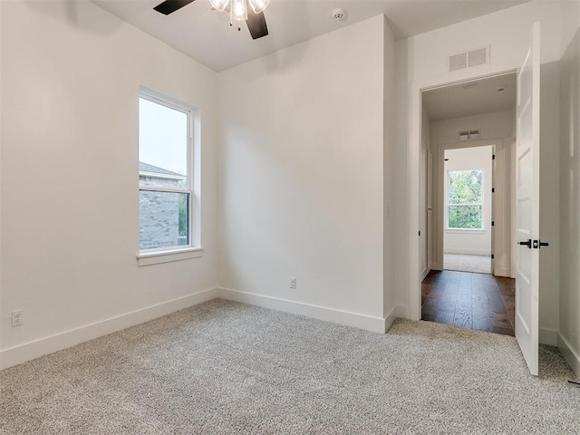 unfurnished room with carpet floors, visible vents, ceiling fan, and baseboards