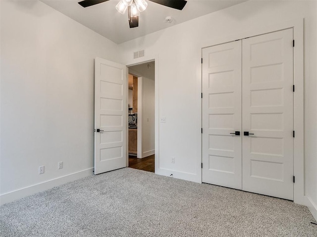 unfurnished bedroom featuring carpet floors, a ceiling fan, visible vents, baseboards, and a closet