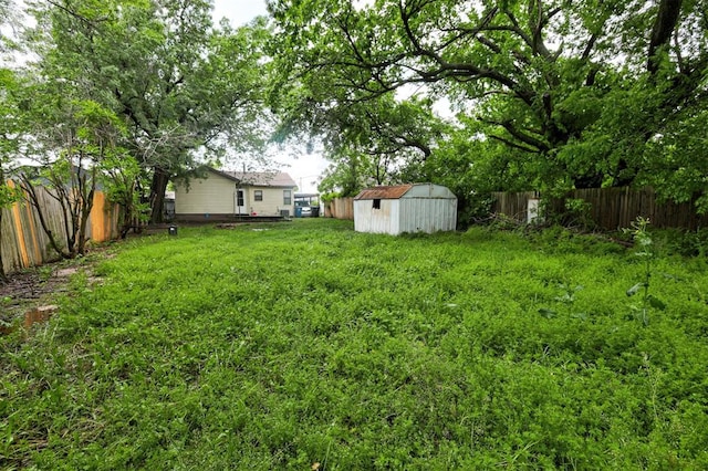 view of yard featuring a fenced backyard, a storage unit, and an outdoor structure