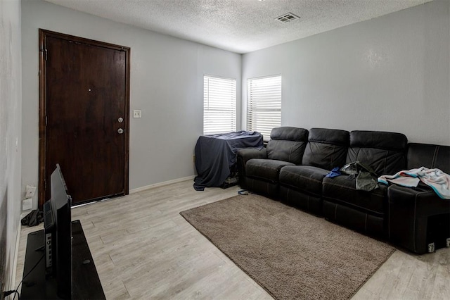 living area featuring visible vents, a textured ceiling, and light wood-style floors