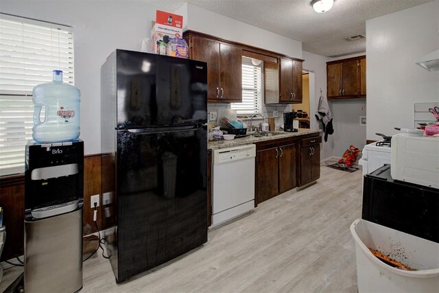 kitchen featuring freestanding refrigerator, light wood-style floors, light countertops, a sink, and dishwasher