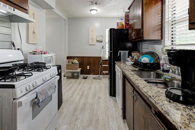 kitchen with a textured ceiling, visible vents, light wood finished floors, under cabinet range hood, and white appliances