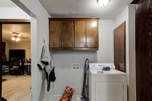 washroom featuring a textured ceiling, cabinet space, light wood-type flooring, and washer / clothes dryer