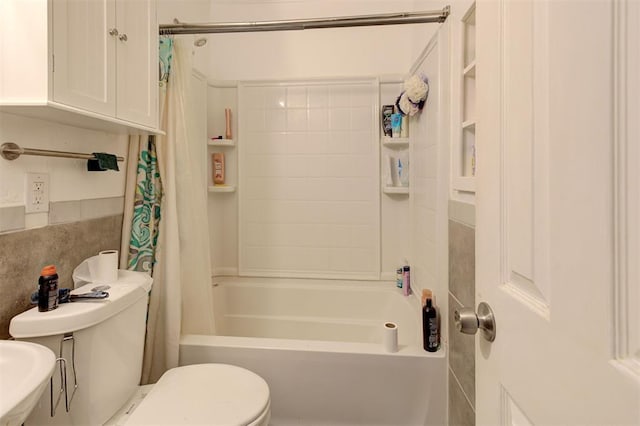 bathroom with shower / tub combo with curtain, a sink, and toilet