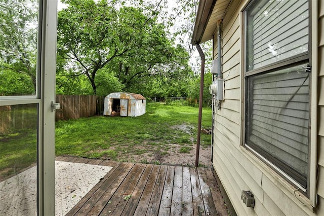 wooden terrace with a storage shed, a yard, an outbuilding, and a fenced backyard