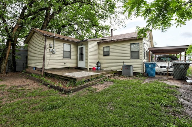 rear view of house with fence, a deck, an attached carport, central air condition unit, and a yard