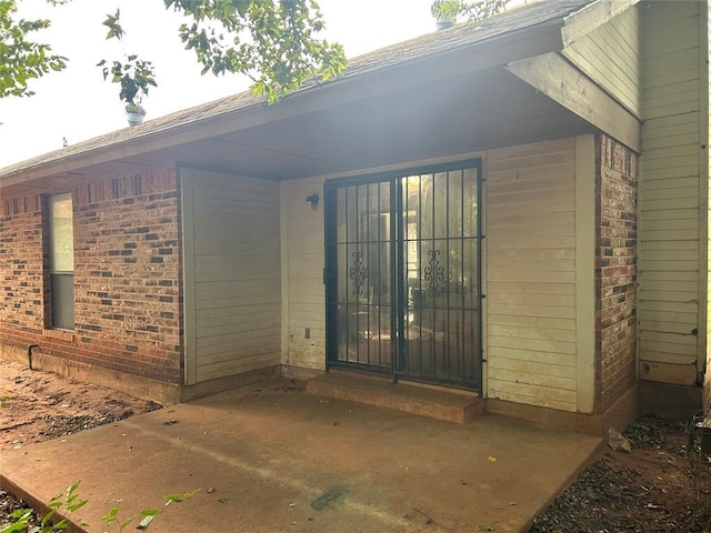 property entrance with brick siding and a patio