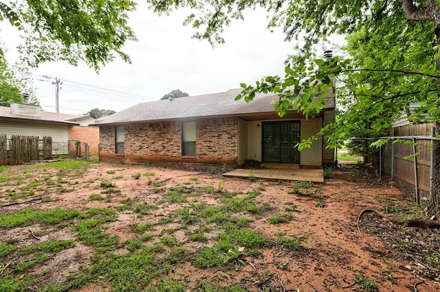 rear view of house featuring brick siding and a fenced backyard