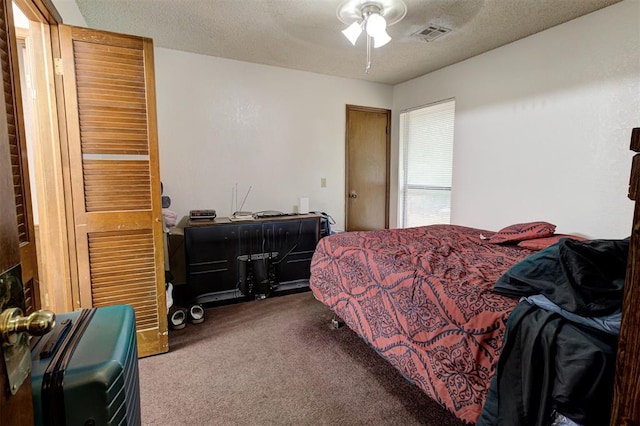 bedroom with a ceiling fan, carpet flooring, a textured ceiling, and visible vents