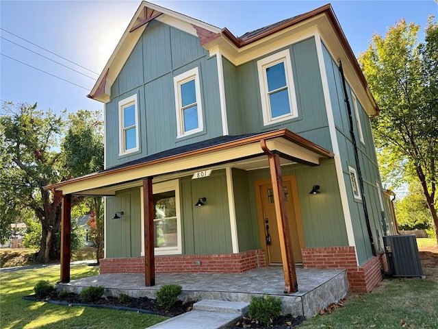 view of front of property with a porch, brick siding, a front lawn, and central AC unit