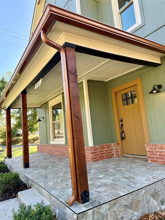 property entrance with covered porch and brick siding