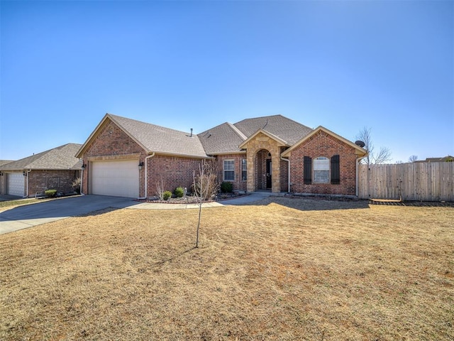 single story home with concrete driveway, brick siding, an attached garage, and fence