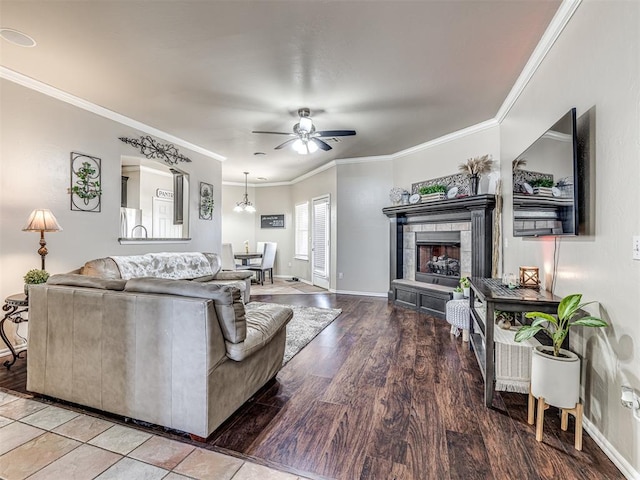 living area featuring baseboards, a tiled fireplace, ceiling fan, ornamental molding, and wood finished floors