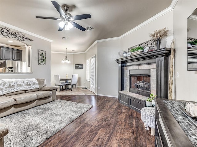 living room featuring a tile fireplace, visible vents, crown molding, and wood finished floors