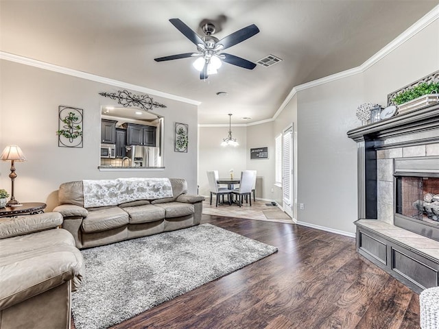 living area with visible vents, baseboards, a ceiling fan, dark wood-style flooring, and crown molding