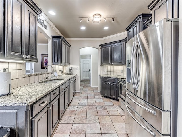 kitchen with crown molding, stainless steel appliances, tasteful backsplash, a sink, and light stone countertops