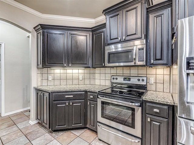 kitchen featuring appliances with stainless steel finishes, arched walkways, light stone countertops, and tasteful backsplash