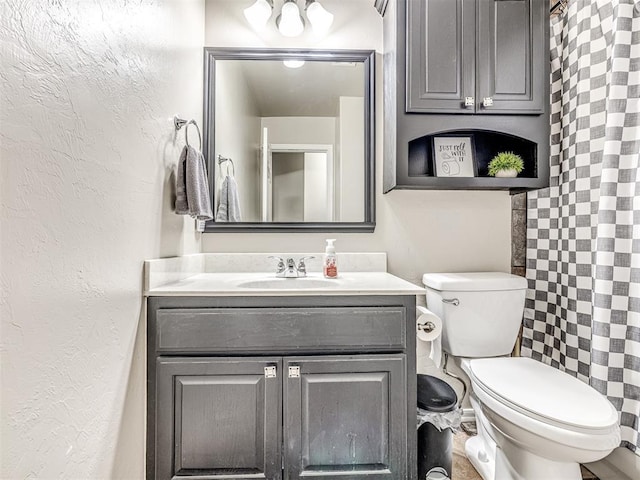 bathroom with toilet, a textured wall, and vanity