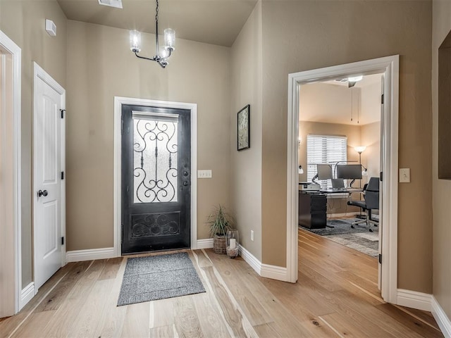 foyer with an inviting chandelier, baseboards, light wood-type flooring, and visible vents