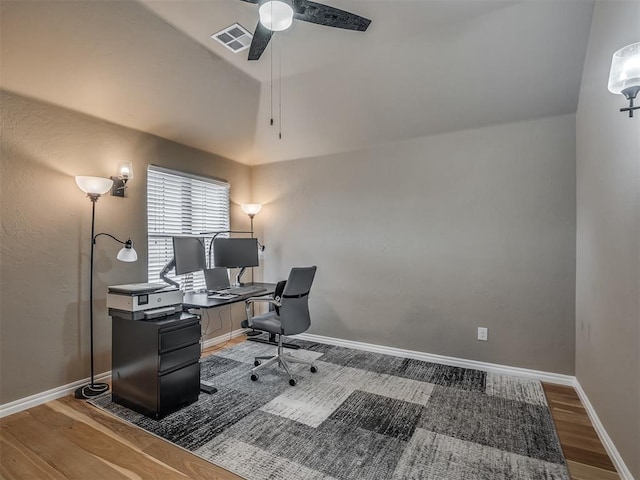 office space with visible vents, baseboards, vaulted ceiling, wood finished floors, and a ceiling fan