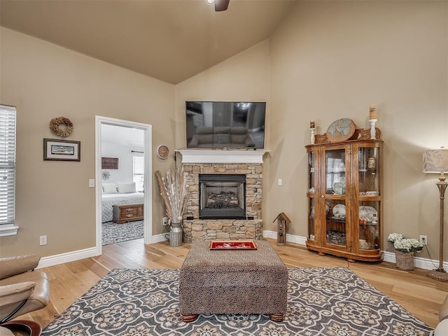 living room featuring a fireplace, baseboards, lofted ceiling, and wood finished floors