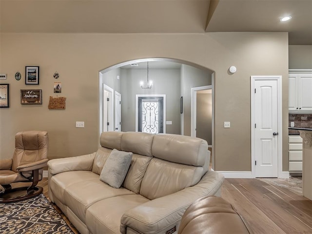 living room featuring recessed lighting, baseboards, arched walkways, and light wood-style floors