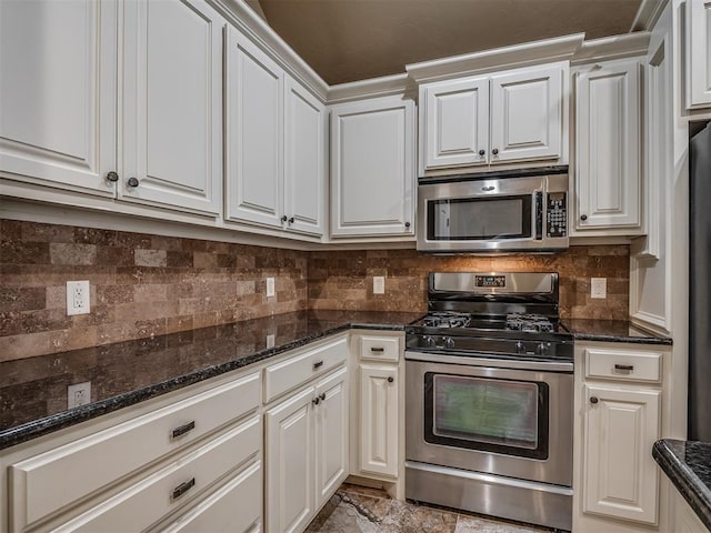 kitchen with stainless steel appliances, dark stone counters, backsplash, and white cabinetry