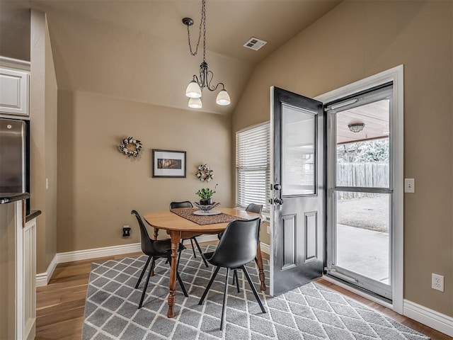 dining room featuring a wealth of natural light, visible vents, lofted ceiling, and wood finished floors