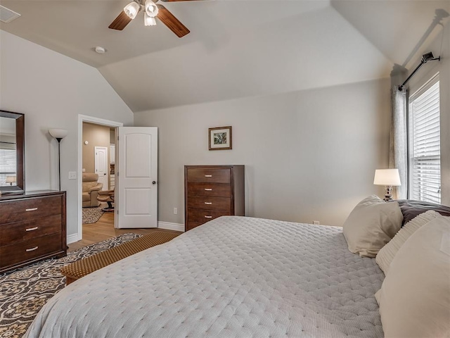 bedroom with visible vents, baseboards, vaulted ceiling, wood finished floors, and a ceiling fan