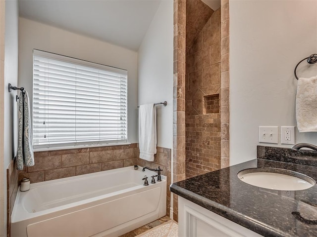 bathroom with tiled shower, lofted ceiling, a bath, and vanity