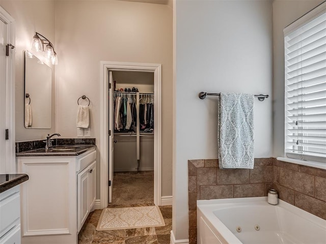 bathroom with vanity, a walk in closet, and a jetted tub