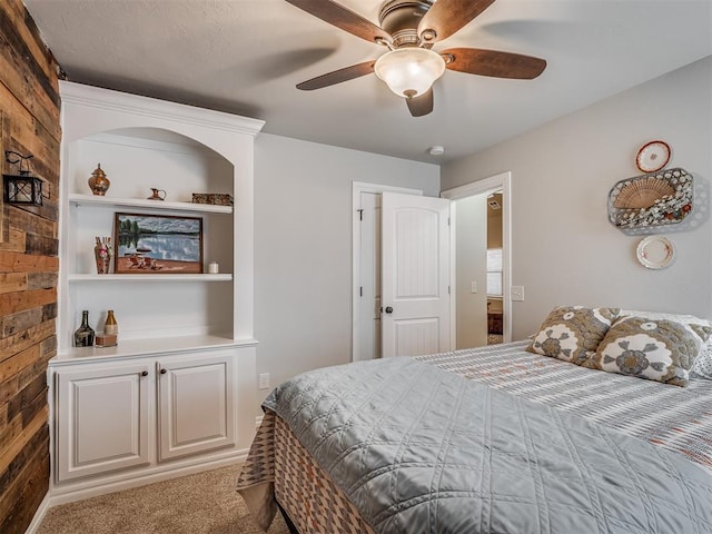 carpeted bedroom featuring wooden walls and ceiling fan