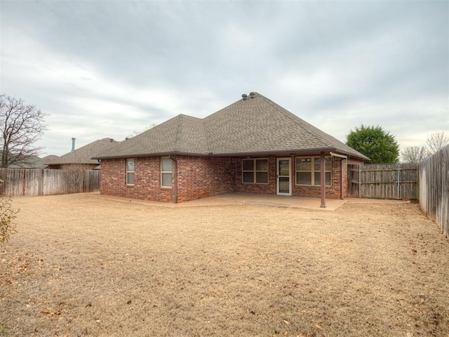 back of house with a patio, a fenced backyard, brick siding, and roof with shingles