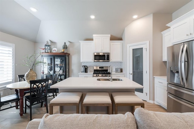 kitchen with a sink, stainless steel appliances, light countertops, white cabinetry, and backsplash