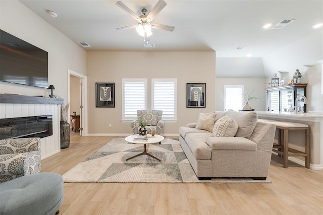 living room with a glass covered fireplace, visible vents, and wood finished floors