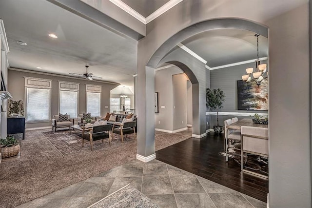 carpeted foyer featuring arched walkways, ornamental molding, and ceiling fan with notable chandelier