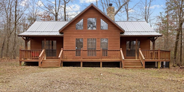 view of front facade featuring faux log siding, a porch, a chimney, and metal roof