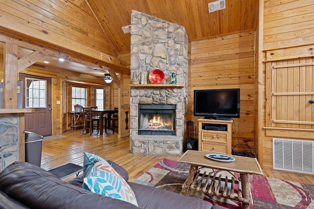 living room featuring visible vents, wooden walls, wood ceiling, and a fireplace