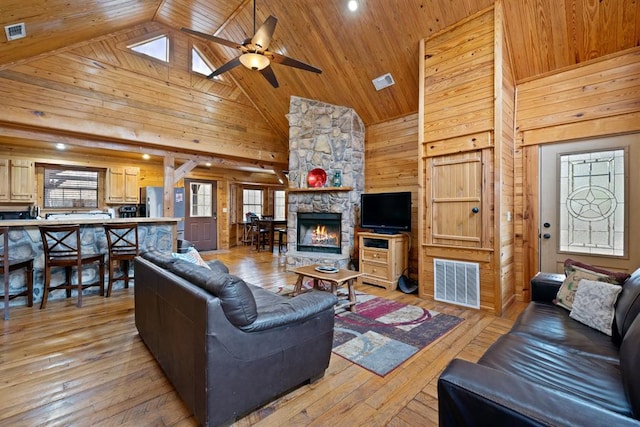 living room with visible vents, wood walls, and light wood-type flooring