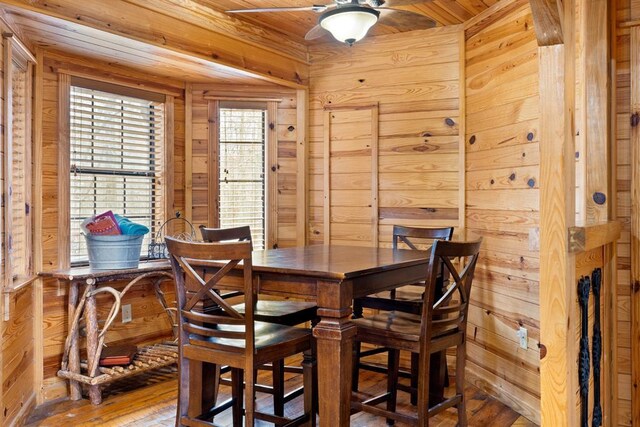 dining room with ceiling fan, wood walls, wooden ceiling, and hardwood / wood-style flooring