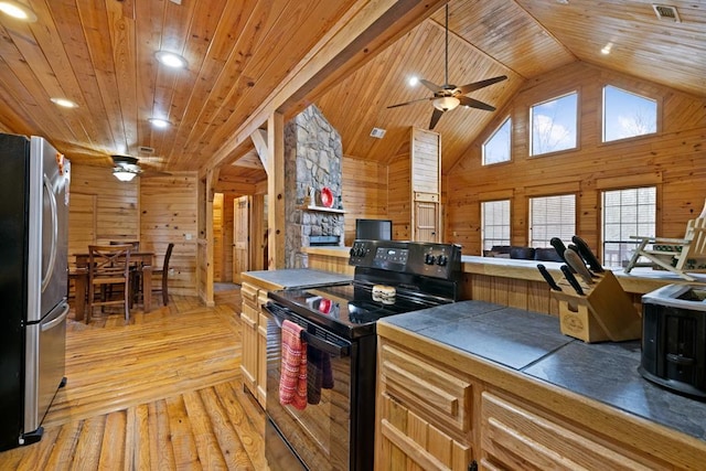 kitchen featuring freestanding refrigerator, wooden walls, black range with electric stovetop, and tile counters