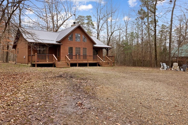 rear view of house with a wooden deck, a chimney, metal roof, driveway, and log veneer siding