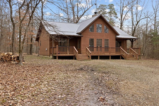 rear view of house featuring log veneer siding, metal roof, and a chimney