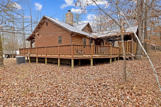 rear view of property featuring a wooden deck, central air condition unit, a chimney, and metal roof