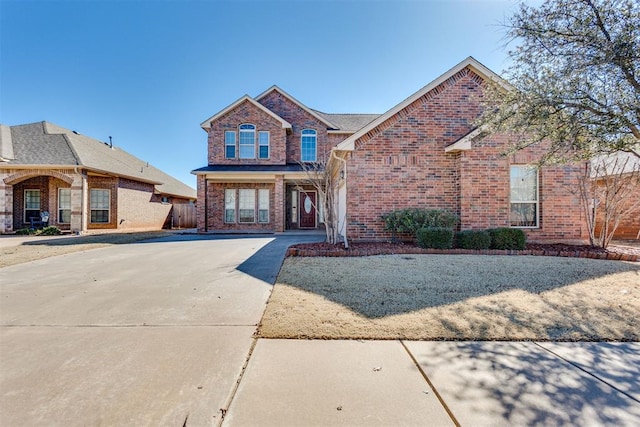 traditional home featuring concrete driveway and brick siding