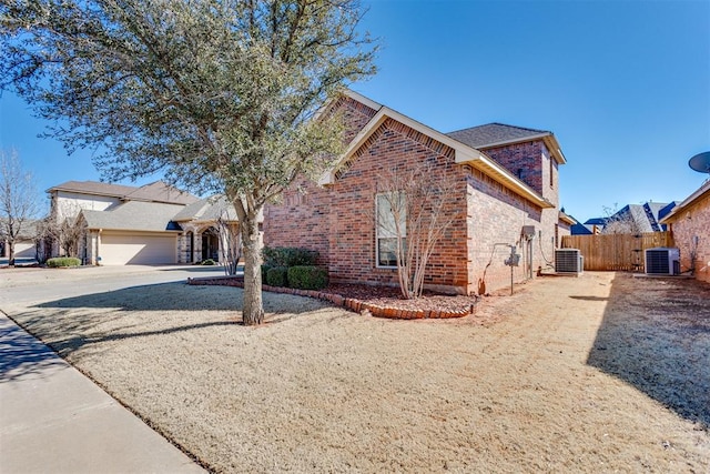 view of front of house featuring central AC, brick siding, fence, and driveway