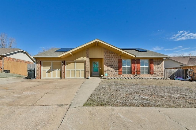 ranch-style home with an attached garage, fence, concrete driveway, and brick siding